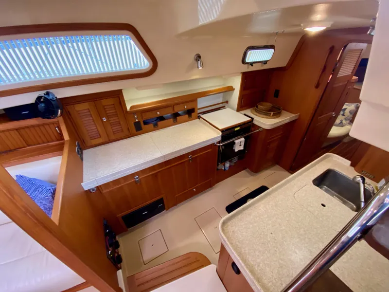 Slide: The Image of 2006 Island Packet 485 Center Cockpit interior with modern kitchen and wooden cabinetry. - 24