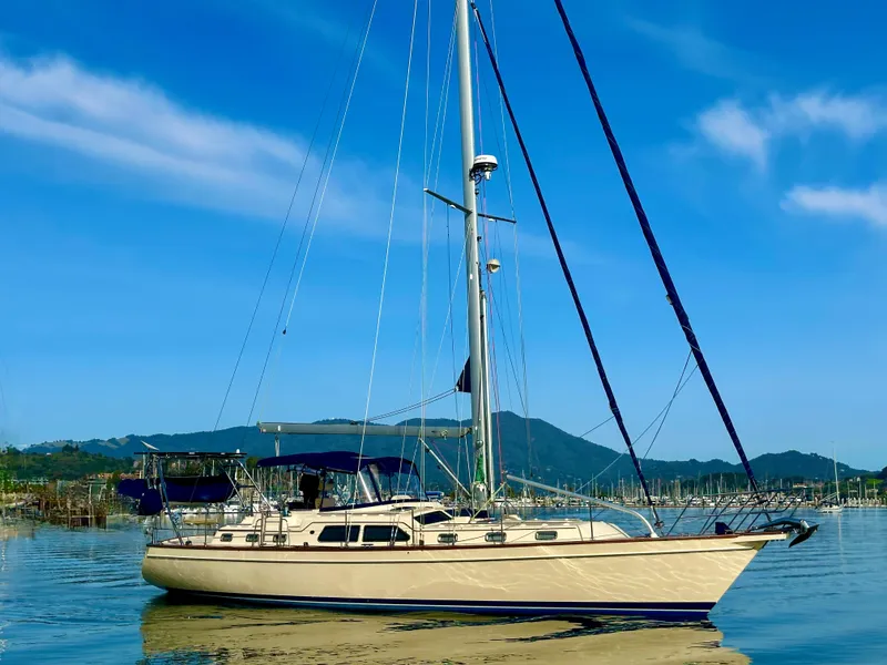 Slide: The Image of 2006 Island Packet 485 Center Cockpit sailboat on calm water with mountain backdrop. - 3