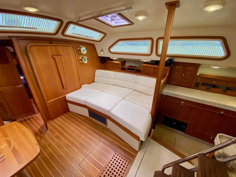 Slide: The Image of 2006 Island Packet 485 Center Cockpit interior with white seating, wood finish, and ample natural light. - 33