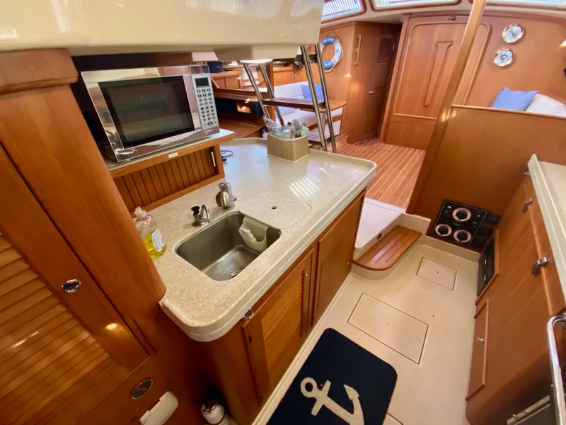 Slide: The Image of 2006 Island Packet 485 Center Cockpit interior with kitchen, sink, and microwave. - 36