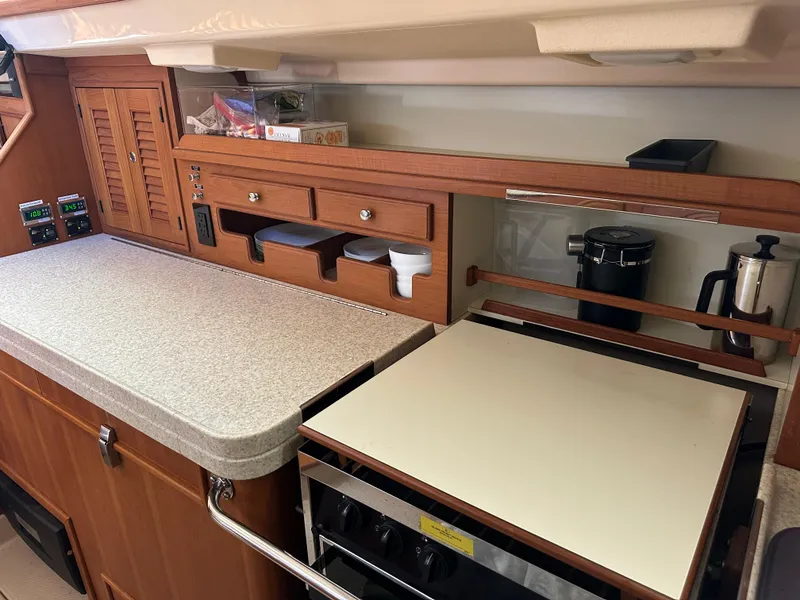 Slide: The Image of 2006 Island Packet 485 Center Cockpit galley with wooden cabinetry and modern appliances. - 38