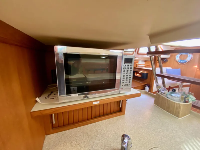 Slide: The Image of Microwave in 2006 Island Packet 485 Center Cockpit yacht interior, featuring wooden cabinetry. - 43