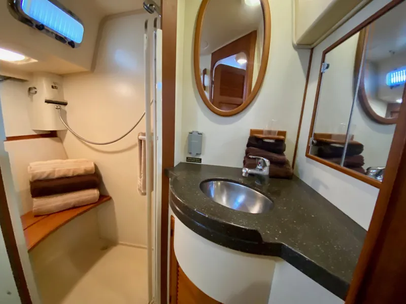 Slide: The Image of 2006 Island Packet 485 Center Cockpit bathroom with sink, mirror, and shower area. - 48