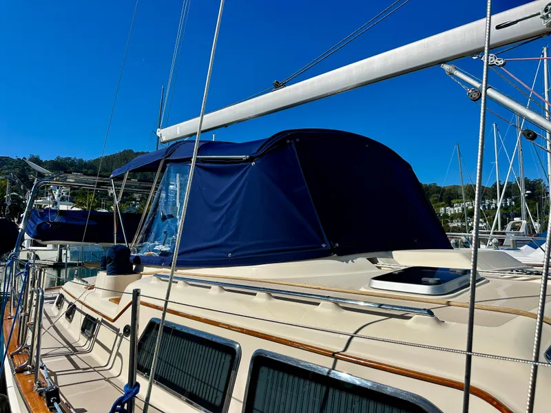 Slide: The Image of 2006 Island Packet 485 Center Cockpit sailboat with blue canopy in marina. - 5