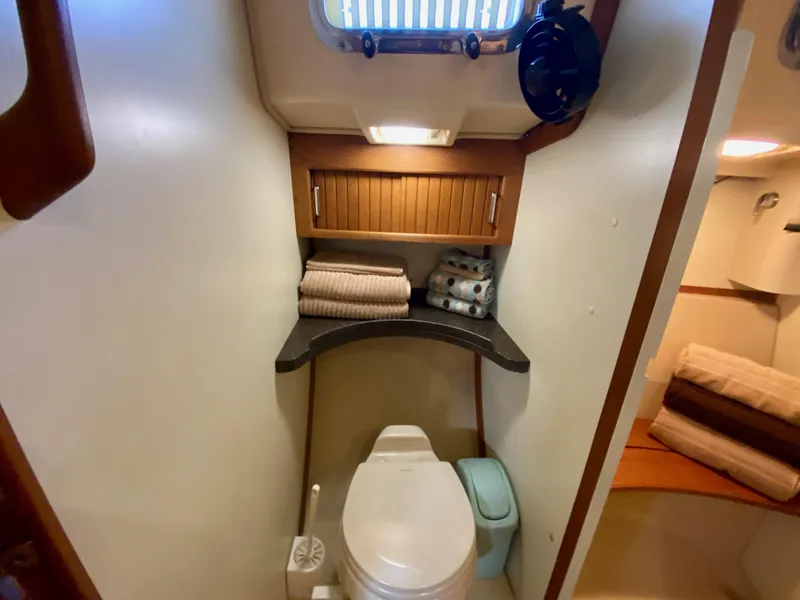 Slide: The Image of 2006 Island Packet 485 Center Cockpit bathroom with toilet, storage, and towels. - 50