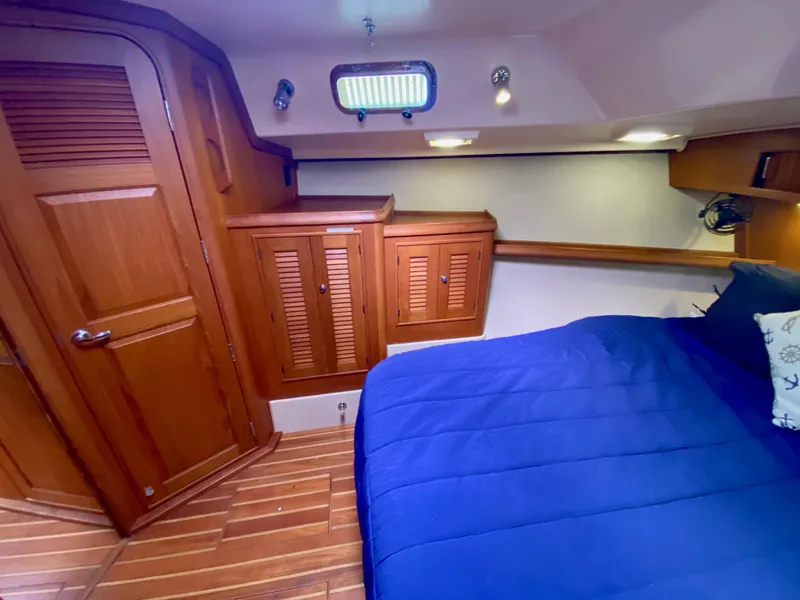 Slide: The Image of Interior of 2006 Island Packet 485 Center Cockpit with wooden cabinetry and blue bedding. - 55