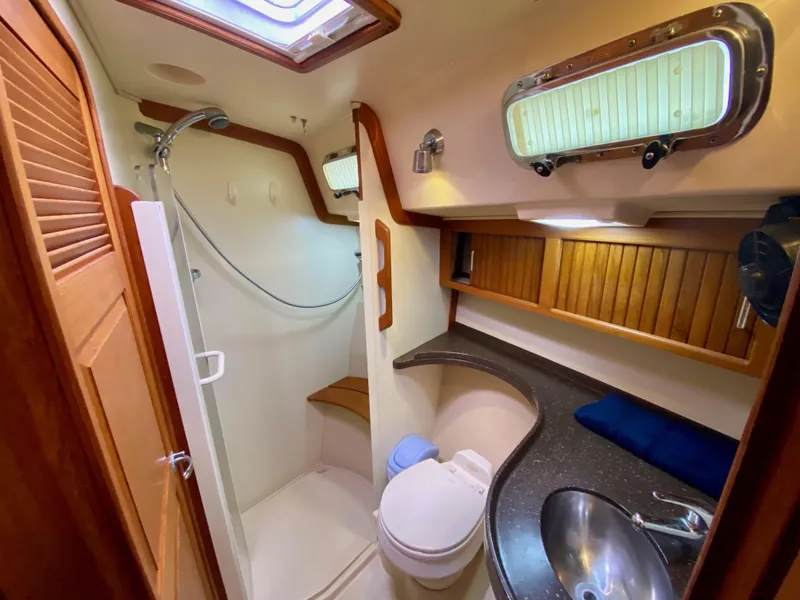 Slide: The Image of Luxurious 2006 Island Packet 485 Center Cockpit bathroom with shower, sink, and wooden cabinetry. - 57