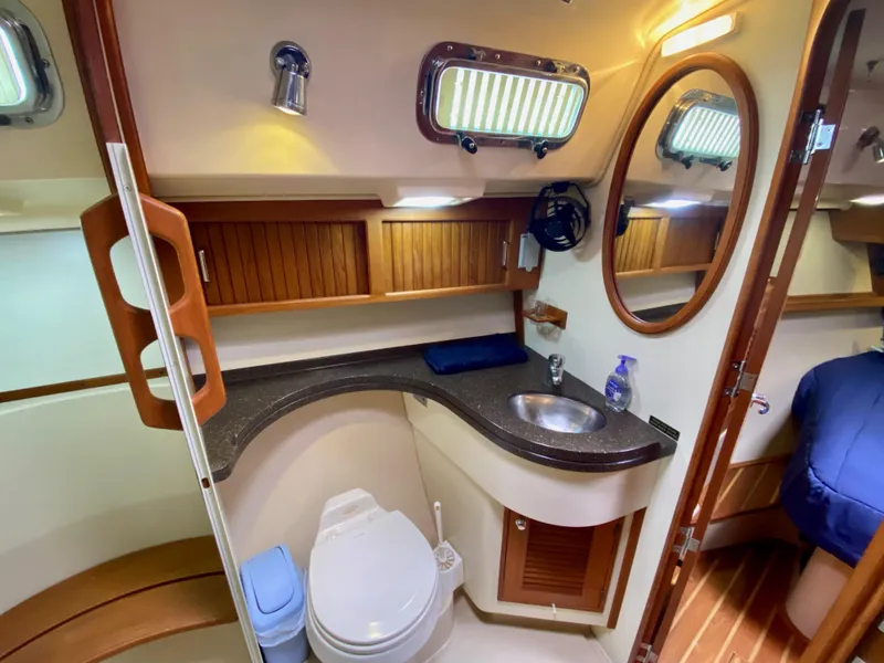 Slide: The Image of 2006 Island Packet 485 Center Cockpit bathroom with sink, toilet, and wooden cabinetry. - 58