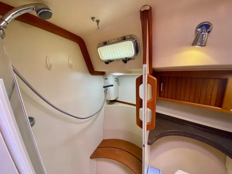 Slide: The Image of 2006 Island Packet 485 Center Cockpit bathroom with shower, wooden accents, and storage. - 59