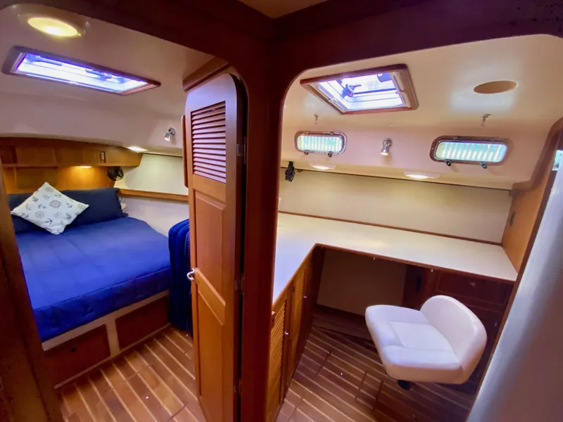 Slide: The Image of 2006 Island Packet 485 Center Cockpit interior with cozy cabin, bed, and desk area. - 60
