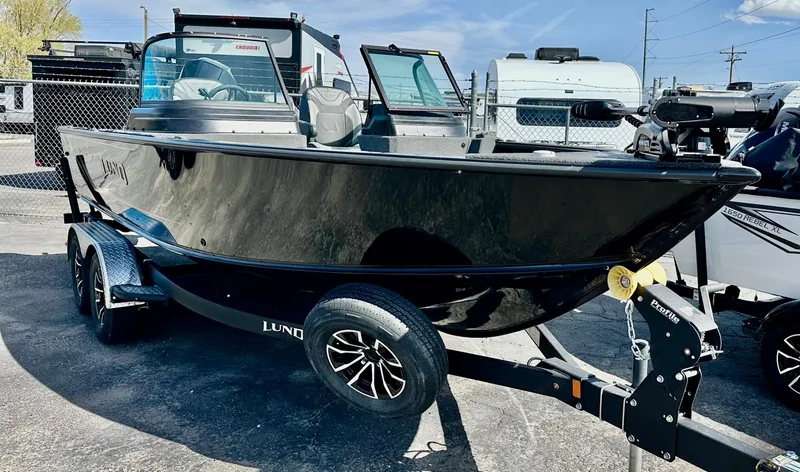 Slide: The Image of 2025 Lund 2075 IMPACT XS boat on trailer, sleek black design, parked outdoors. - 1