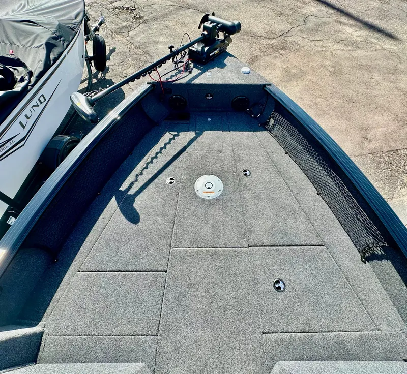 Slide: The Image of 2025 Lund 2075 IMPACT XS boat deck with trolling motor, carpeted surface, and storage compartments. - 15