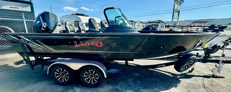 Slide: The Image of 2025 Lund 2075 IMPACT XS boat on trailer, black exterior, parked outdoors. - 2