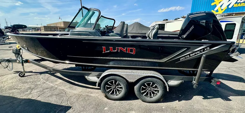 Slide: The Image of 2025 Lund 2075 IMPACT XS boat on trailer, black exterior, parked outdoors. - 5