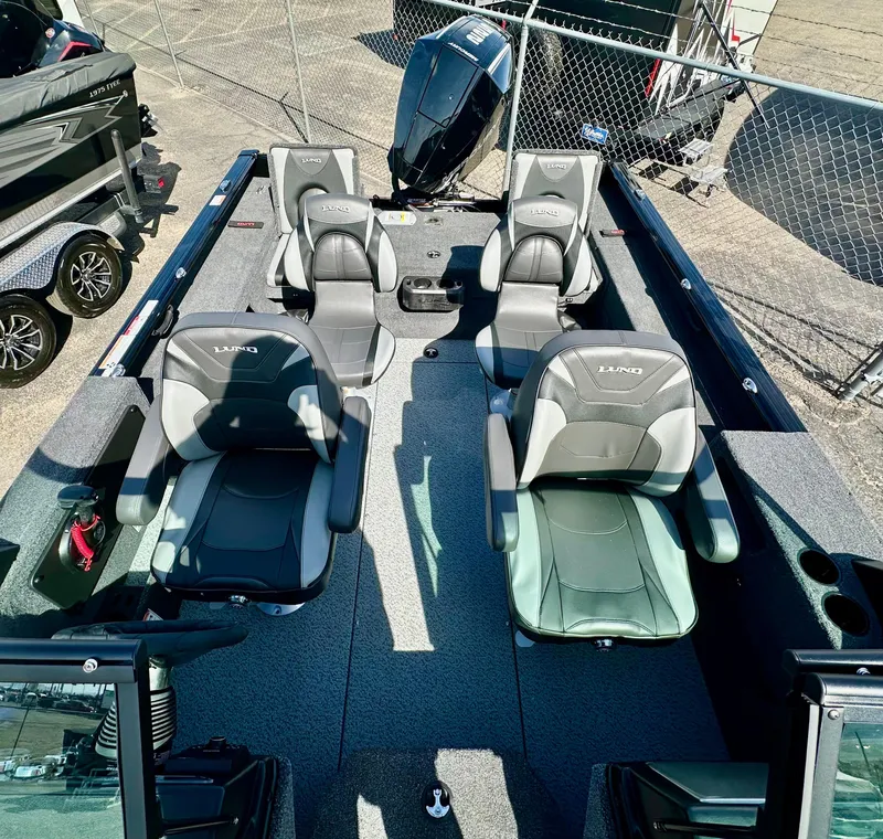 Slide: The Image of 2025 Lund 2075 IMPACT XS boat interior with four seats, parked near a fence. - 8