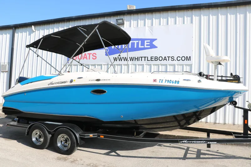 Slide: The Image of 2009 Hurricane FunDeck 226 OB boat on trailer, blue and white, parked outside dealership. - 10