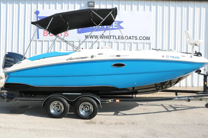 Slide: The Image of 2009 Hurricane FunDeck 226 OB boat with blue hull on trailer, displayed outdoors. - 11
