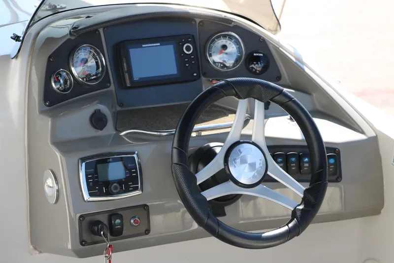 Slide: The Image of Steering console of a 2018 Stingray 212 SC boat with gauges and controls. - 18