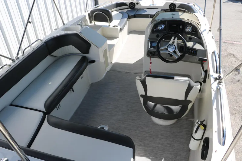 Slide: The Image of 2018 Stingray 212 SC boat interior with seating, steering wheel, and dashboard. - 19