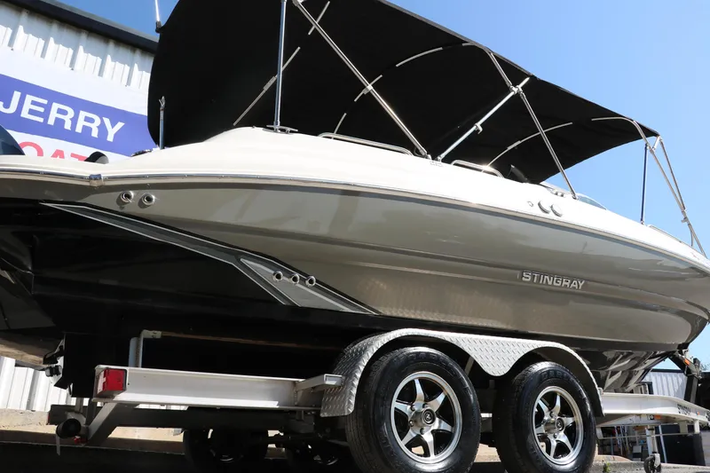 Slide: The Image of 2018 Stingray 212 SC boat on trailer with black canopy, side view. - 3