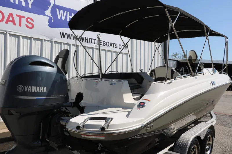 Slide: The Image of 2018 Stingray 212 SC boat with Yamaha engine, parked on a trailer under a canopy. - 4