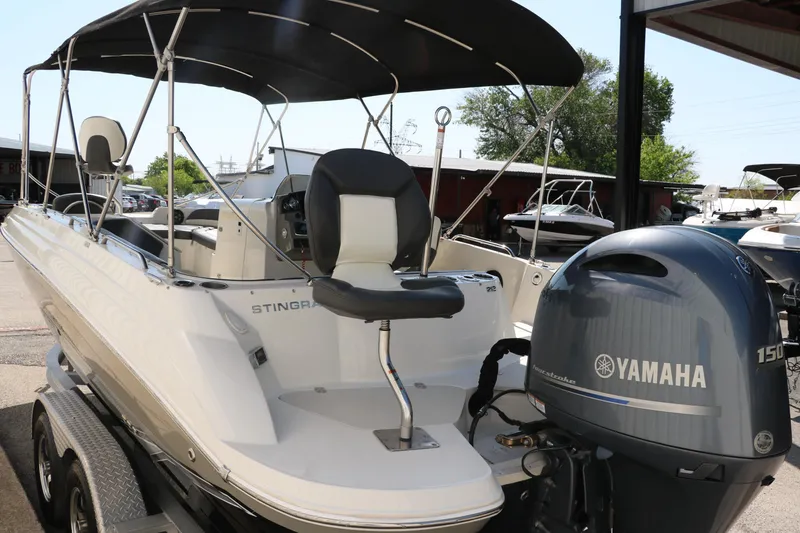 Slide: The Image of 2018 Stingray 212 SC boat with Yamaha 150 engine, docked under a canopy. - 6