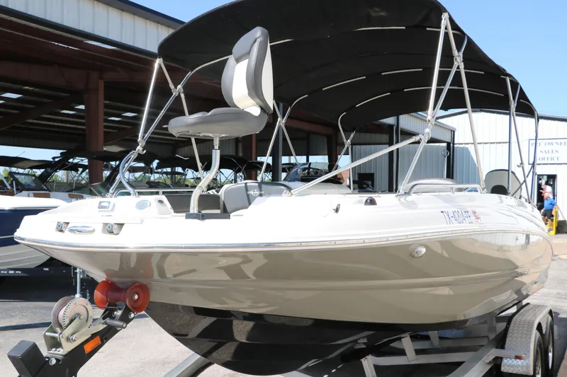 Slide: The Image of 2018 Stingray 212 SC boat on trailer with canopy, parked in marina. - 8