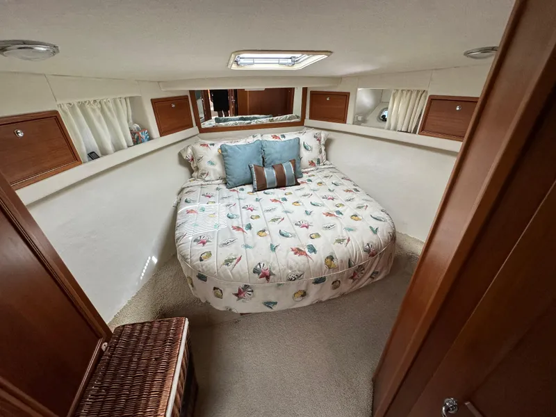 Slide: The Image of Cozy bedroom in 1998 Riviera 43 Open Flybridge yacht with floral bedding and wooden accents. - 10