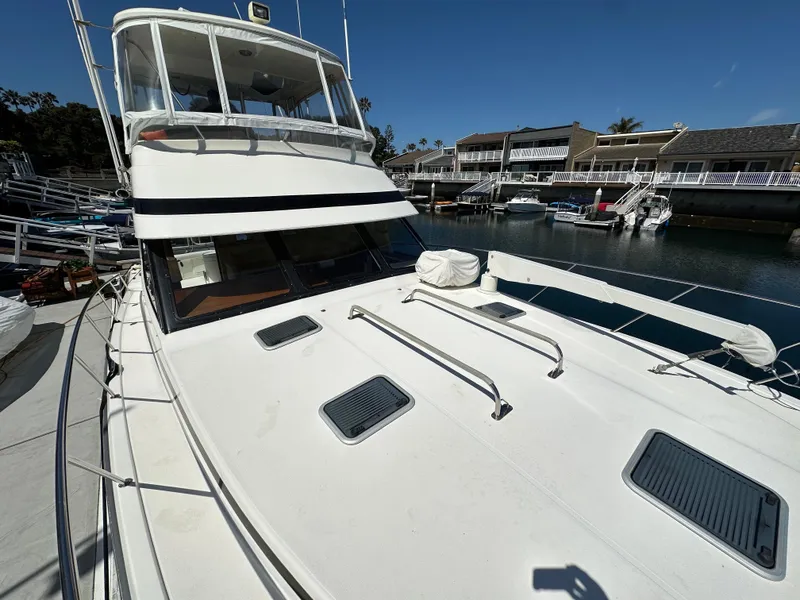 Slide: The Image of 1998 Riviera 43 Open Flybridge yacht docked in a marina under clear blue skies. - 3