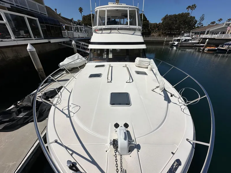 Slide: The Image of 1998 Riviera 43 Open Flybridge yacht docked in a marina, showcasing spacious deck and sleek design. - 4