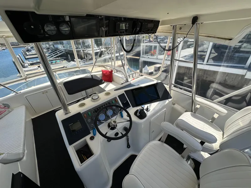 Slide: The Image of 1998 Riviera 43 Open Flybridge helm with modern controls and marina view. - 6