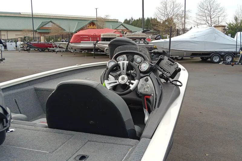 Slide: The Image of 2022 Tracker Pro Team 190 TX boat interior with steering wheel and dashboard in a marina. - 2