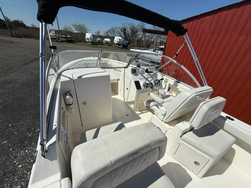 Slide: The Image of 2023 Cobia 220 Dual Console boat interior with white seating and steering console. - 11