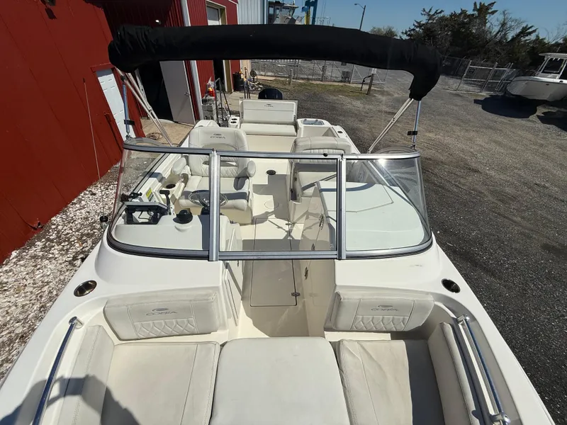 Slide: The Image of 2023 Cobia 220 Dual Console boat with white seating and black canopy. - 14