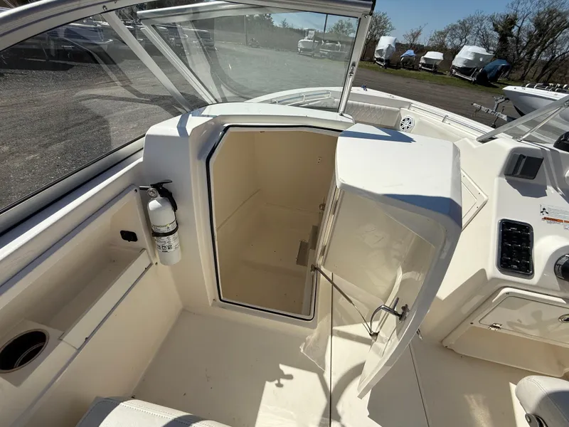 Slide: The Image of 2023 Cobia 220 Dual Console boat interior with open storage compartment. - 16