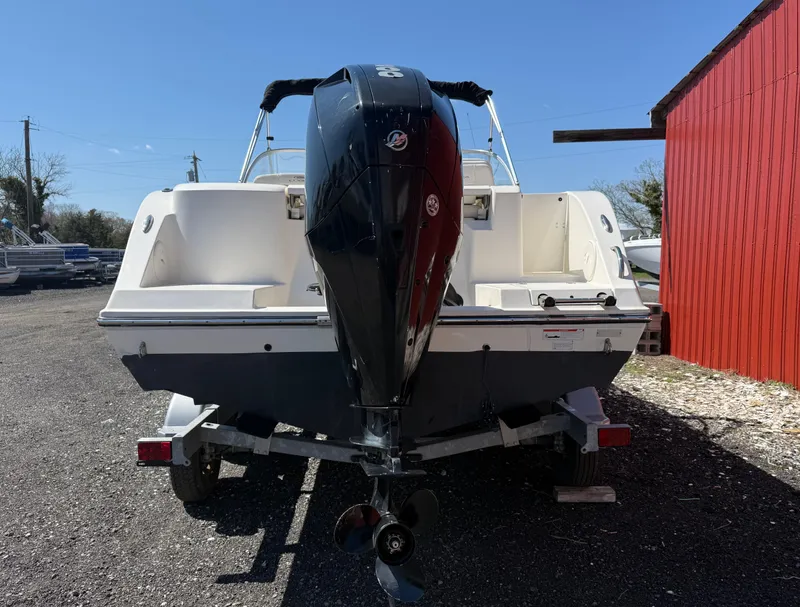 Slide: The Image of 2023 Cobia 220 Dual Console boat with outboard motor, parked on a trailer. - 4
