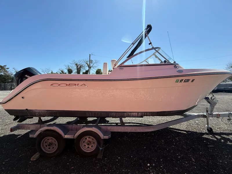 Slide: The Image of 2023 Cobia 220 Dual Console boat on trailer under clear blue sky. - 6