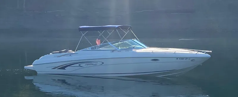 The Image of 2001 Rinker 272 Captiva boat on calm water with a canopy and sleek design. - 0