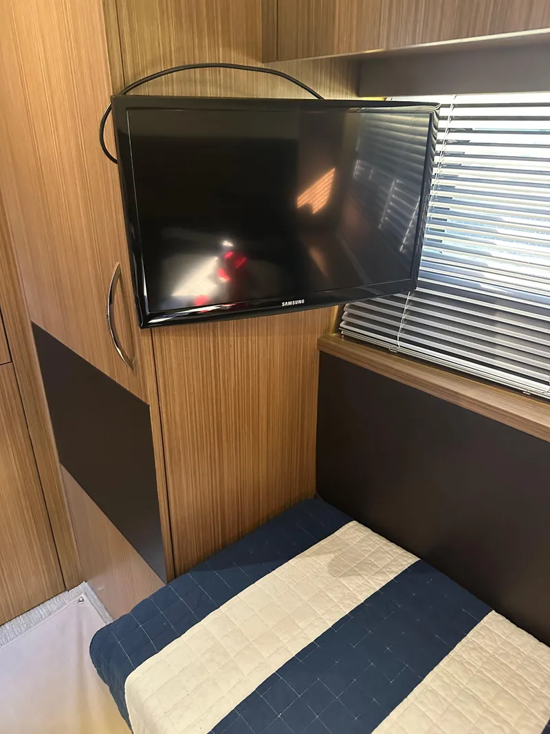 Slide: The Image of Interior of 2016 Sea Ray L590 Fly yacht with mounted TV and striped bedding. - 37