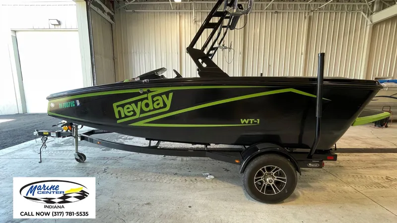 Slide: The Image of 2019 Heyday WT-1 boat in a garage, black with green accents, on a trailer. - 1