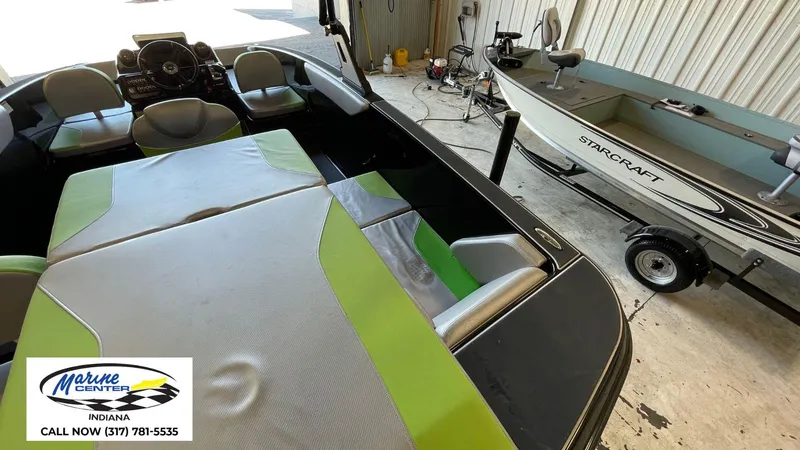 Slide: The Image of 2019 Heyday WT-1 boat interior with green seating, next to a Starcraft boat in a garage. - 7