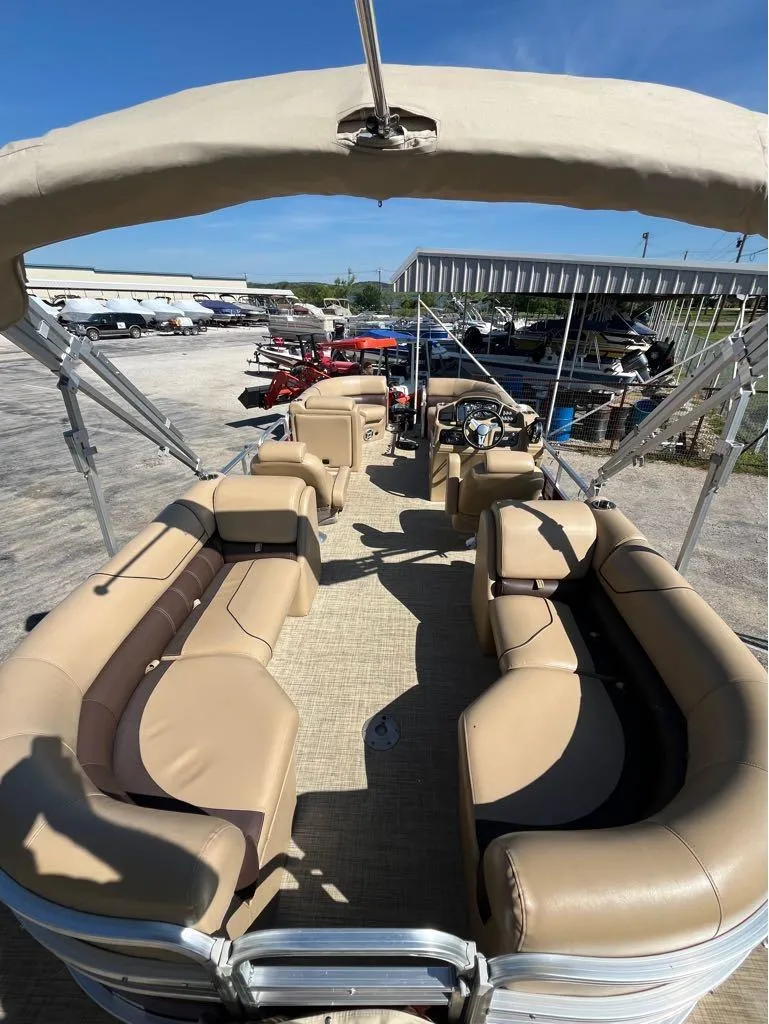 Slide: The Image of 2019 Lowe SS230W pontoon boat with beige seating and canopy, parked outdoors. - 7