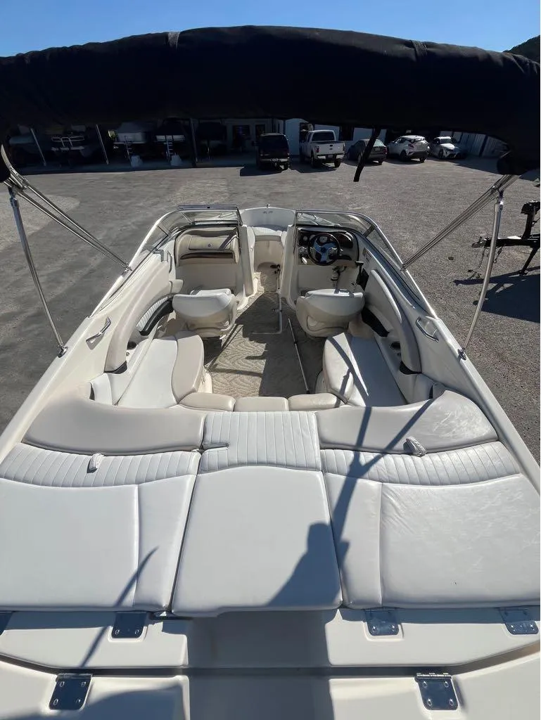 Slide: The Image of 2007 Glastron GXL235 boat interior with white seating and steering wheel, under a black canopy. - 2