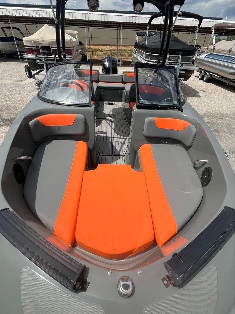 Slide: The Image of 2019 Bayliner 210 EL boat with orange and gray seating, docked in a marina. - 4