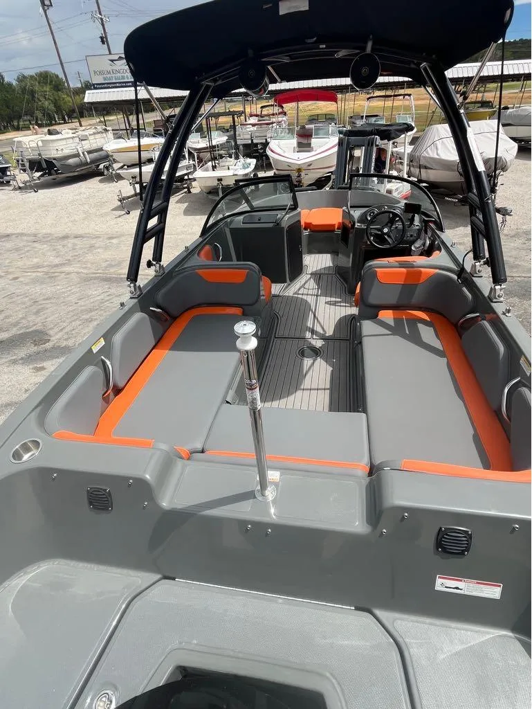 Slide: The Image of 2019 Bayliner 210 EL boat with gray and orange seating, docked at a marina. - 6