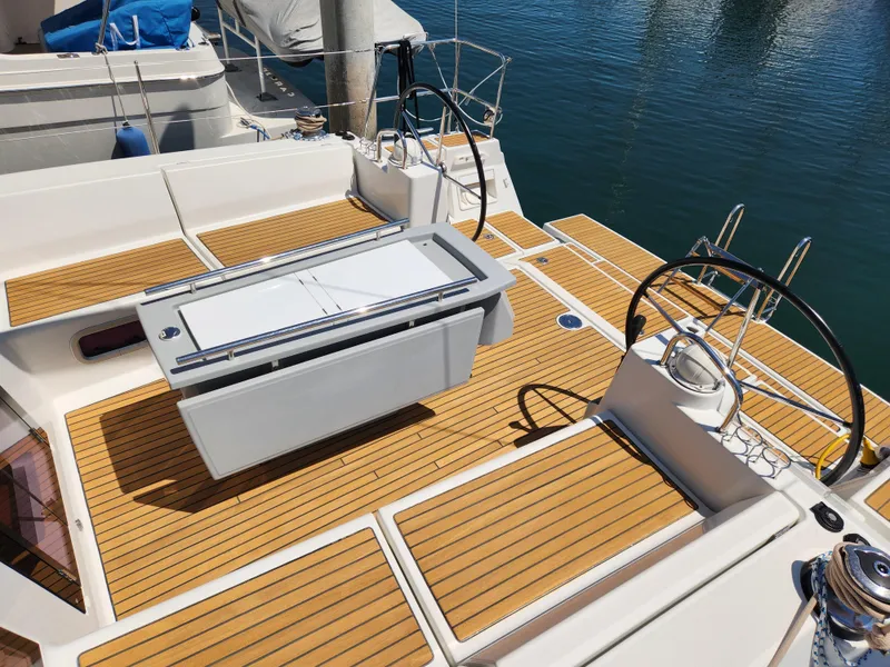 Slide: The Image of Beneteau Oceanis 41 sailboat deck with teak flooring, dual steering wheels, and cockpit table. - 19
