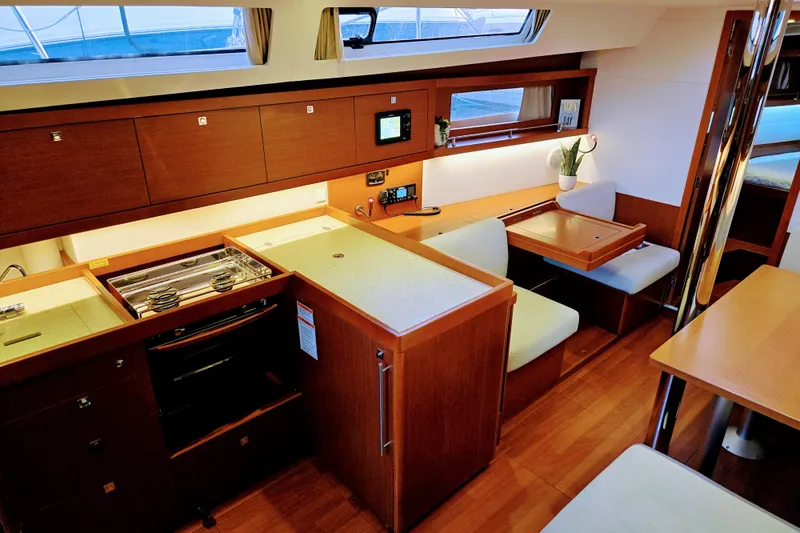 Slide: The Image of Interior of 2013 Beneteau Oceanis 41 yacht, featuring a modern kitchen and dining area. - 26