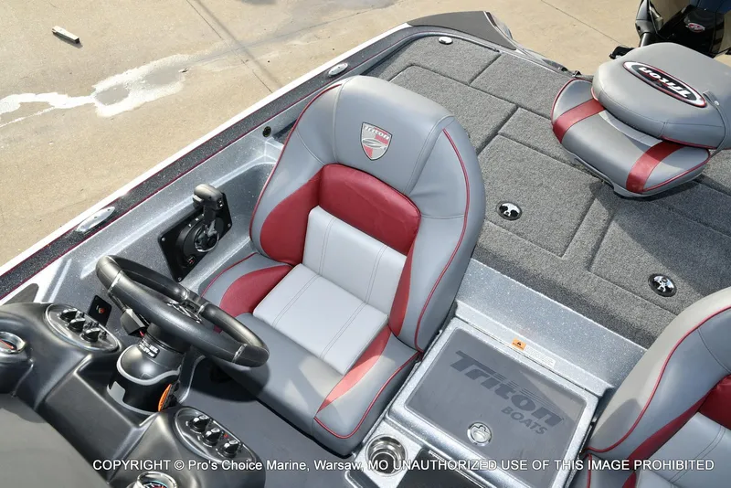 Slide: The Image of 2024 Triton 18 TRX boat interior with gray and red seating, steering wheel, and carpeted deck. - 42