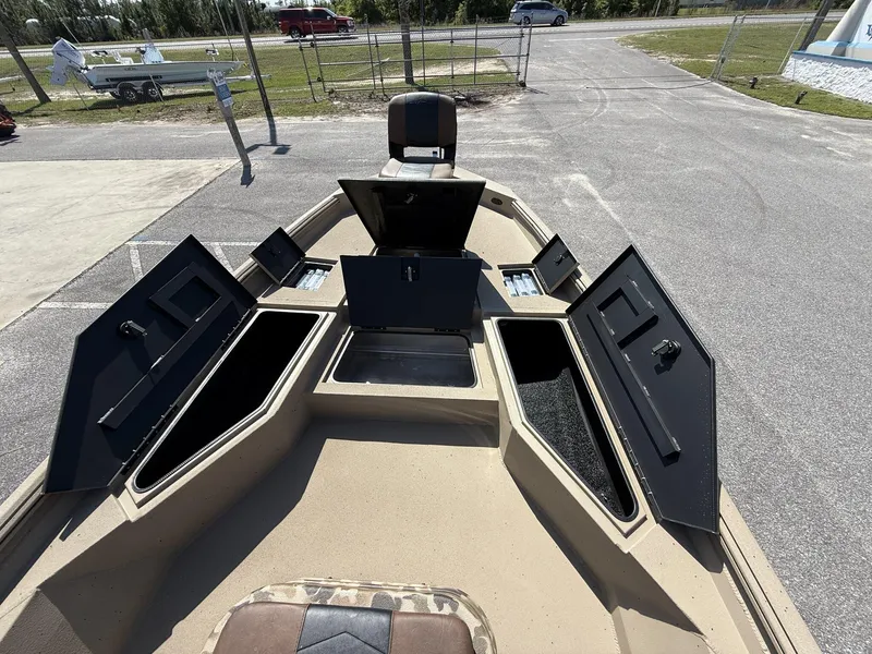 Slide: The Image of 2025 Excel New Bay Pro 230 boat with open storage compartments, parked outdoors. - 7