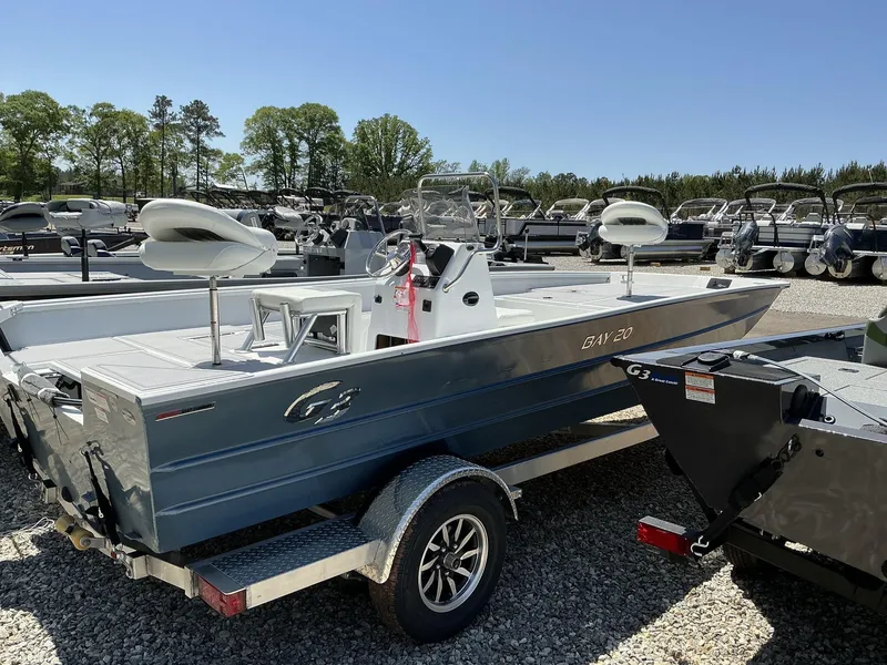 Slide: The Image of 2025 G3 Bay 20 boat on trailer, parked outdoors, surrounded by trees and other boats. - 5